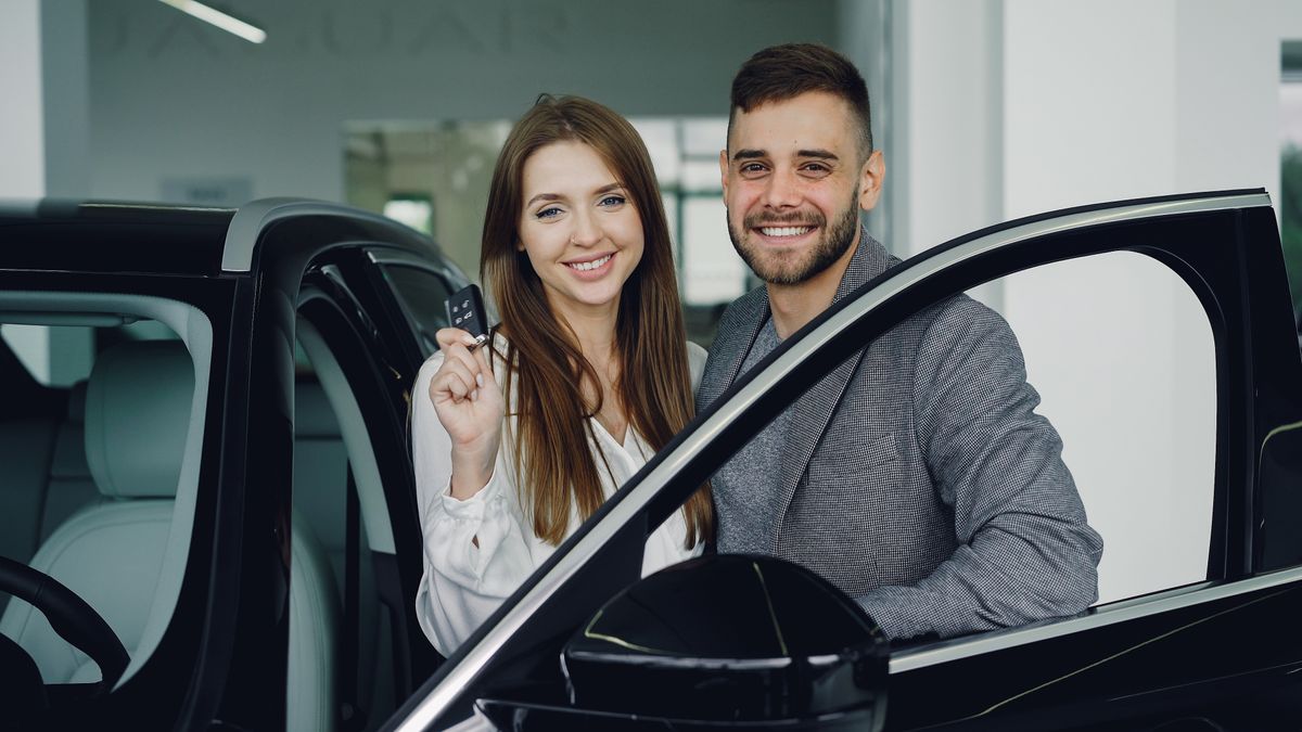 Laiminga pora automobilių salone su naujo automobilio rakteliais